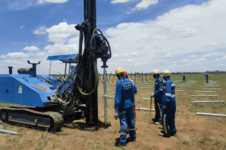 Workers installing helical screw piles for solar panels with machinery on a solar farm site