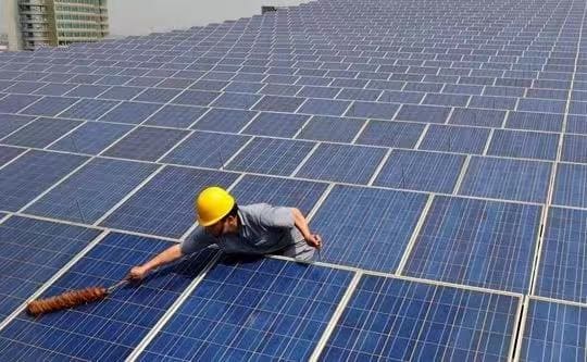 A man cleaning the ground mounted solar panels