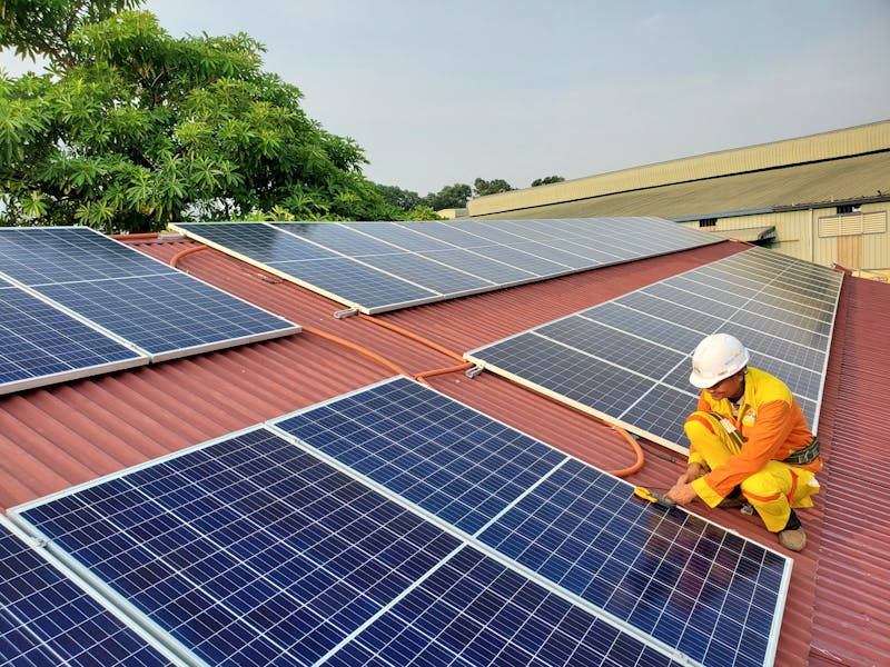 A solar technician performs maintenance on rooftop solar panels enhancing energy efficiency.